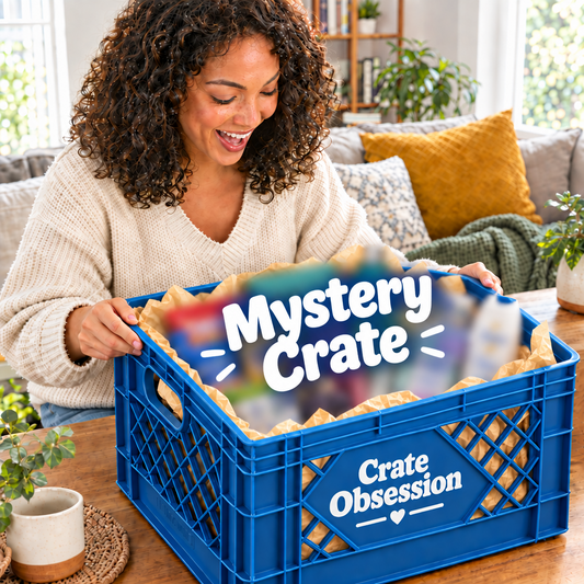 A woman smiling as she opens a crate labeled Mystery Crate from Crateobsession filled with Mystery items that are blurry so its a Mystery. The items are curated gift assortment, including bath towels, toiletries, a candle, and packaged items, in a bright living room setting
